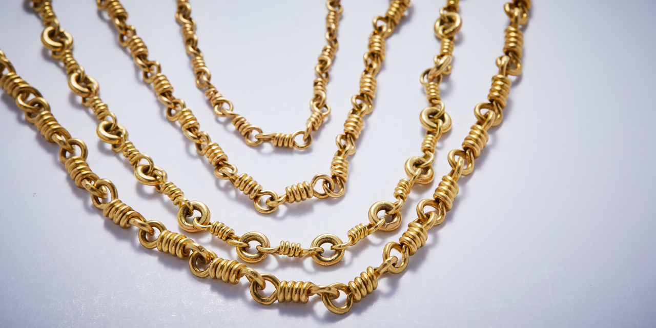 A series of gold chained necklaces against a white background
