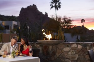 A couple enjoys dinner at dusk with Scottsdale's Praying Monk rock formation in the background