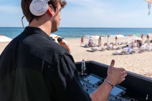 A DJ spins a turntable facing The Beach Club at Gurney's Montauk Resort