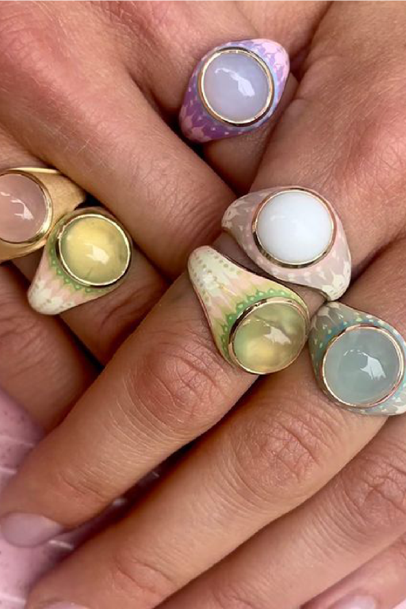Two folded hands adorned with pastel colored rings from K. Wit