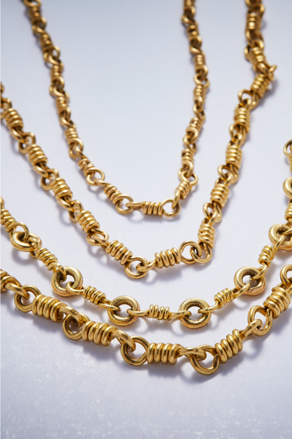 A series of gold chained necklaces against a white background