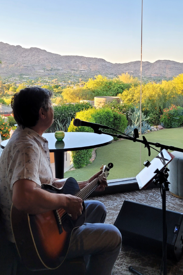 A man plays guitar at jade bar at Sanctuary Camelback Mountain with Scottsdale's valley views in the background.