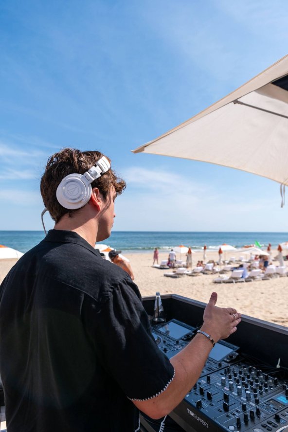 A DJ spins a turntable facing The Beach Club at Gurney's Montauk Resort