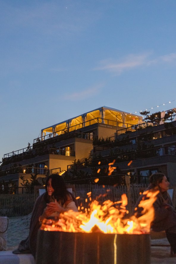 A bonfire glows on the sand at dusk at Gurney's Montauk Resort