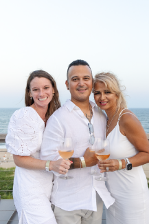 A group of three dressed in white pose for a photo with the ocean in the background at Gurney's Montauk